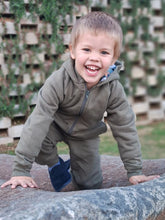 Load image into Gallery viewer, Child wearing a green onesie in cotton fleece with a hood.
